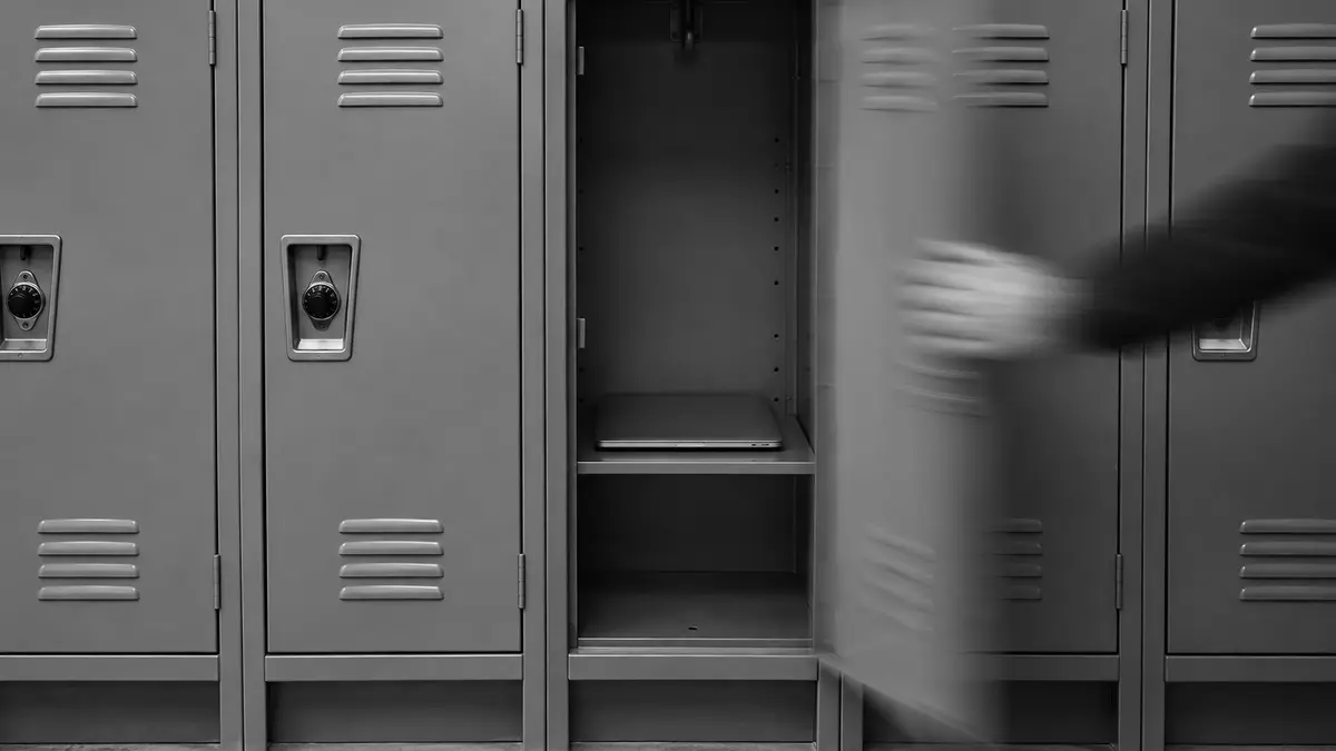 A blurred hand moves an open locker door beside a row of metal lockers.
